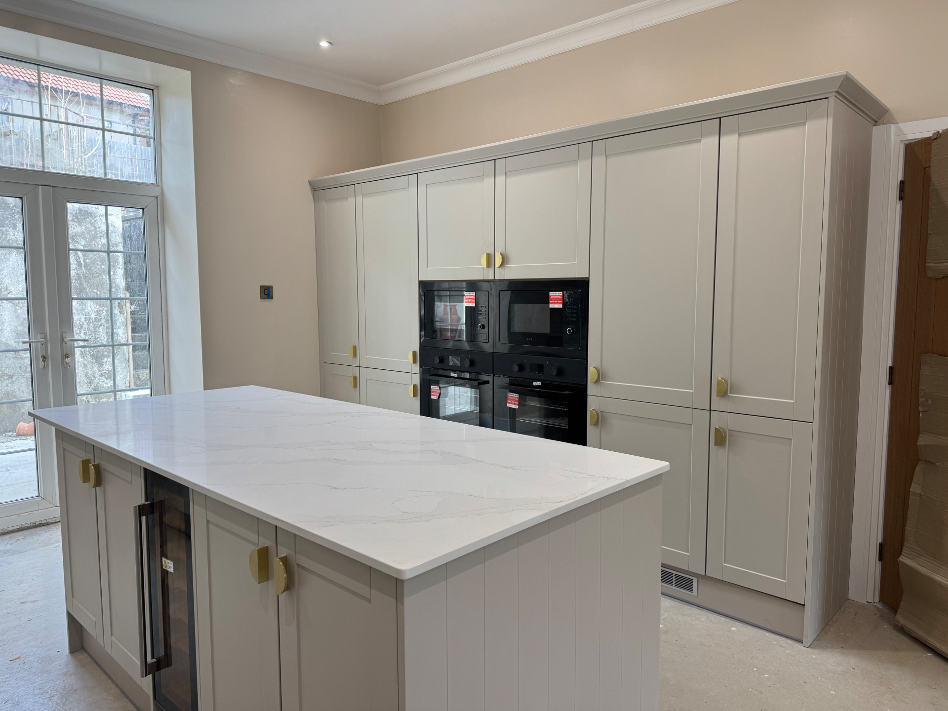 Wide view of the Reno project kitchen showing island, tall cabinetry and appliance housing