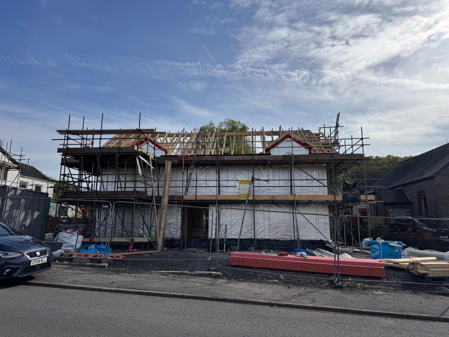 Front elevation of the Rhos new build in Neath with scaffolding and roof framing in progress