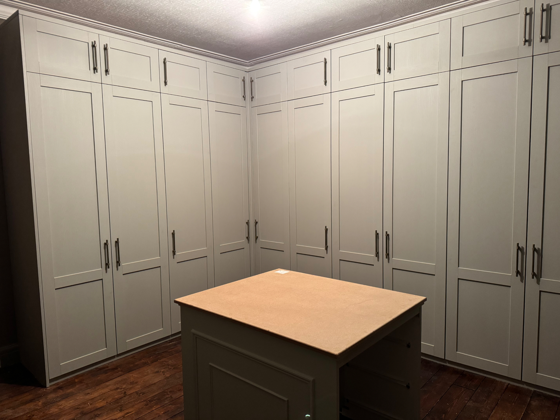 Wide view of bespoke fitted wardrobes with shaker doors and central island unit